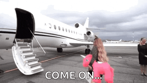 a woman in a pink unicorn costume is walking towards a private jet on the tarmac .