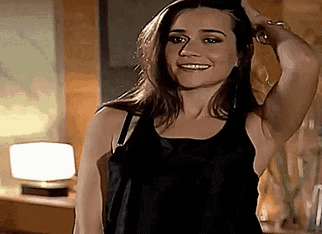 a woman in a black tank top is smiling