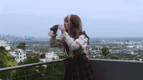 a woman is looking through binoculars at a city