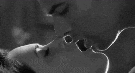 a man and a woman are kissing each other in a black and white photo .