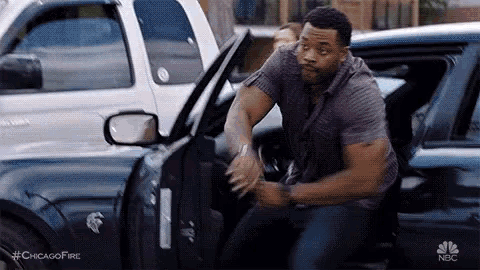 a man is getting out of a police car with his hands on the door .