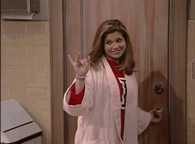 a woman wearing a white coat and a red sweater with the letter m on it