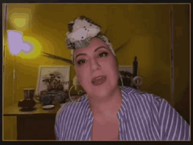 a woman wearing a head scarf and a striped shirt looks at the camera .