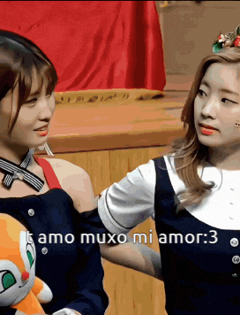 two girls are standing next to each other and one of them is holding a stuffed animal that says amo muxo mi amor