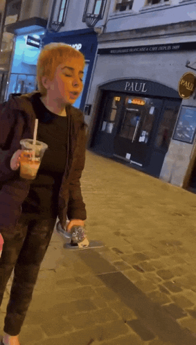 a woman is walking down a cobblestone street in front of a paul restaurant