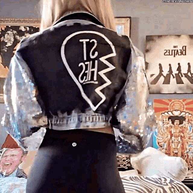 a woman is wearing a jacket with a broken heart on it
