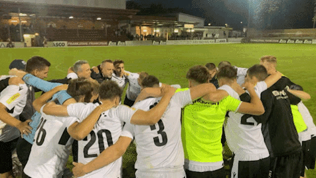a group of soccer players huddle together with the number 3 on their backs