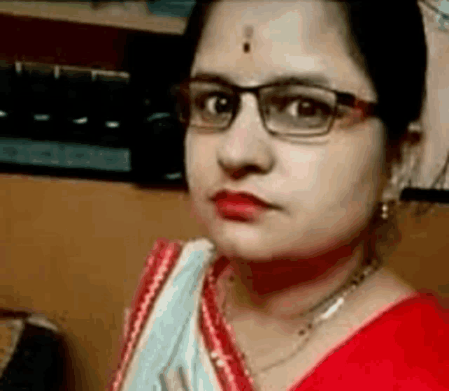 a close up of a woman wearing glasses and a red sari .