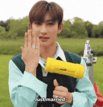 a young man with a ring on his finger is holding a yellow hammer and saying `` just married '' .