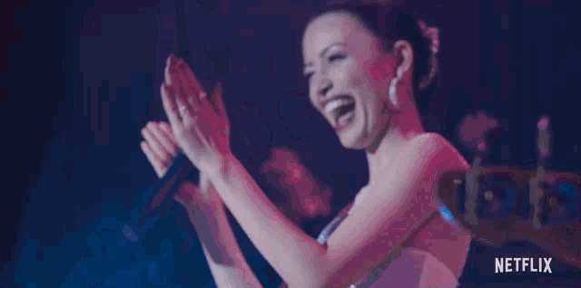 a woman singing into a microphone with the netflix logo behind her