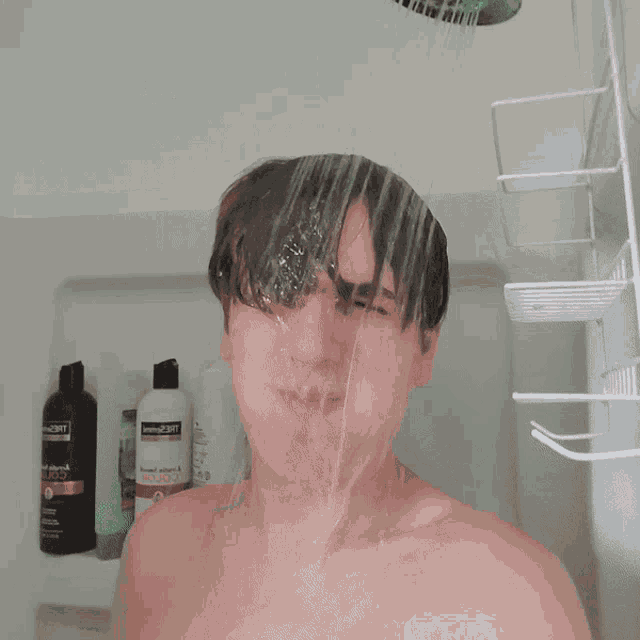 a man taking a shower with a bottle of tresemme shampoo in the background