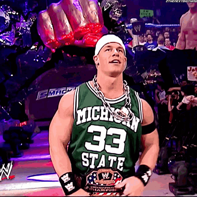 a man wearing a green michigan state jersey stands in front of a crowd