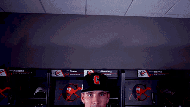 a man wearing a baseball cap with the letter c on it stands in a locker room