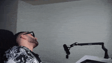 a man wearing sunglasses sits in front of a microphone