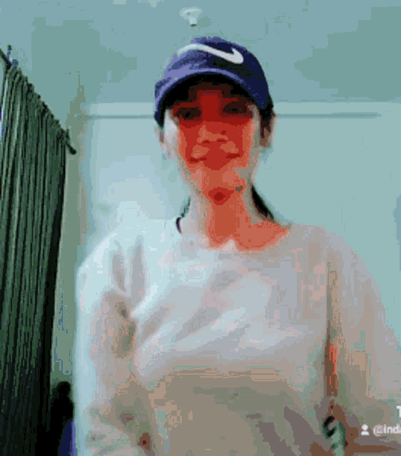 a woman wearing a nike hat and a white shirt is smiling