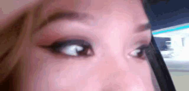 a close up of a woman 's eyes with a phone in the background