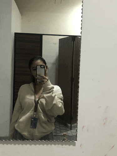 a woman taking a picture of herself in a mirror with her phone