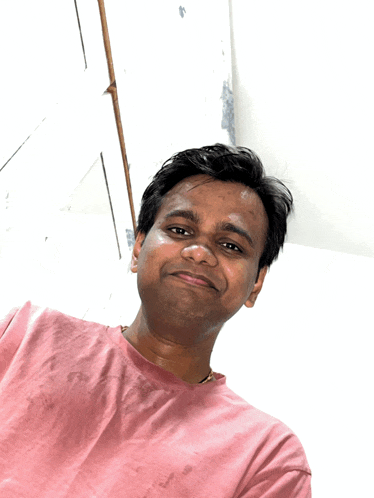 a man wearing a pink t-shirt is smiling for the camera