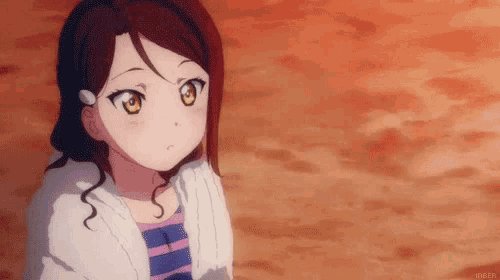 a girl with brown hair and yellow eyes is wearing a white cardigan and a striped shirt .