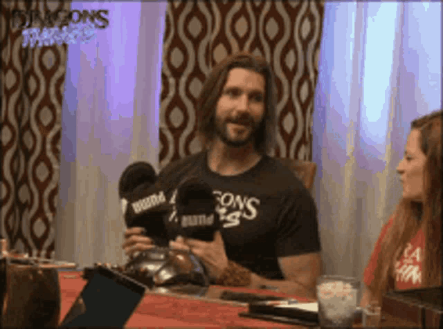 a man in a dungeons and dragons t-shirt holds a microphone