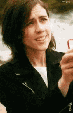 a woman in a black jacket is taking a picture of herself with her phone .