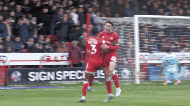a soccer player with the number 3 on his jersey celebrates with another player