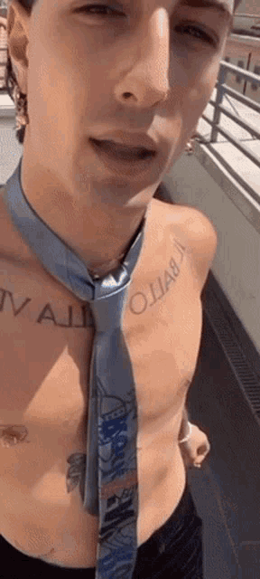 a shirtless man with a tie around his neck and a tattoo on his chest