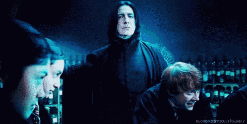 a group of people are standing in a dark room looking at a man in a black jacket .