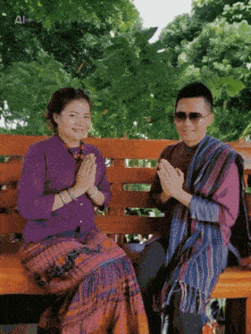 a man and a woman are sitting on a bench with their hands folded in prayer