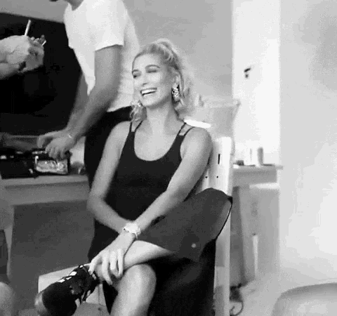 a woman is sitting in a chair laughing while a man holds her leg .