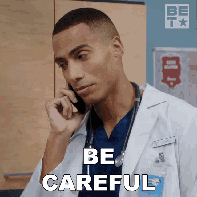 a man in a lab coat talking on a cell phone with be careful written on the bottom