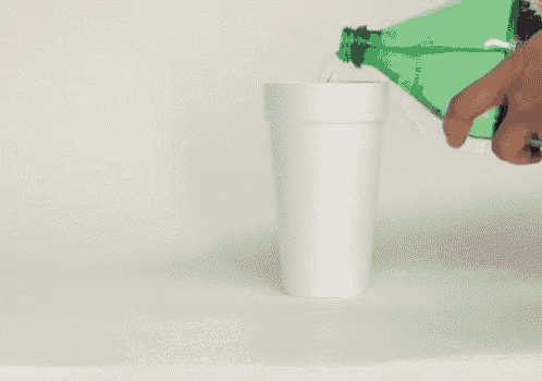a bottle of soda is being poured into a cup of ice .