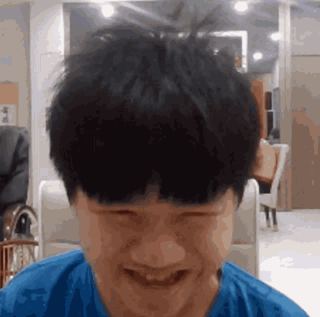 a young man in a blue shirt is smiling and looking at the camera