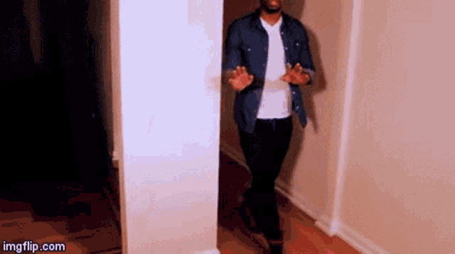 a man in a denim shirt is walking down a hallway