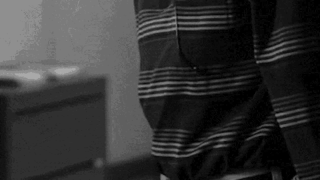 a black and white photo of a person wearing a striped shirt and pants .