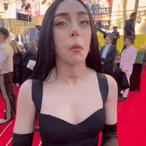 a woman standing on a red carpet with a sign in the background that says grill