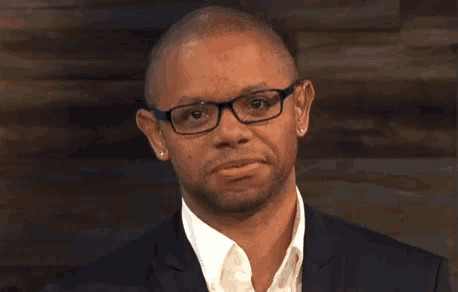 a man wearing a suit and glasses is making a funny face .