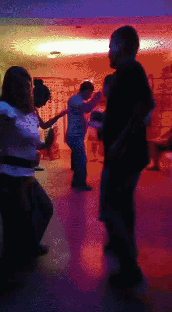 a group of people are dancing in a dark room with red and blue lights