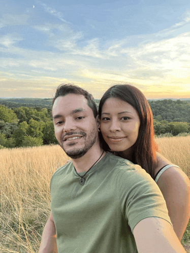 a man and a woman are posing for a photo in a field