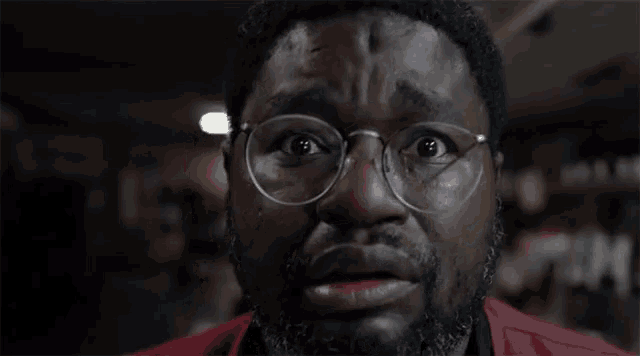 a man wearing glasses and a red shirt is making a funny face