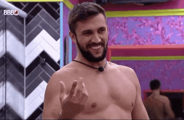 a shirtless man with a beard is smiling in a room with the letters bb on the bottom