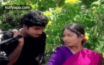 a man and woman are standing next to each other in a forest .