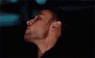 a close up of a man 's face with a beard in a dark room .