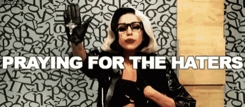 a woman is praying for the haters while wearing a black jacket and gloves .