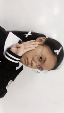 a girl covering her face with her hands wearing a sweater that says off white