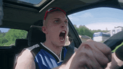 a man driving a car with his mouth open and wearing sunglasses