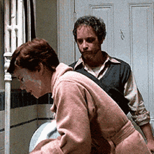 a man and a woman are standing next to a toilet