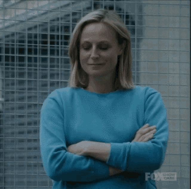 a woman in a blue sweater with her arms crossed
