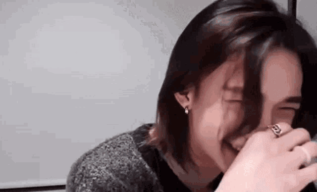 a close up of a person covering their mouth with their hand and laughing .