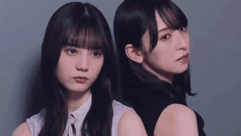 two young women are standing next to each other looking at the camera .
